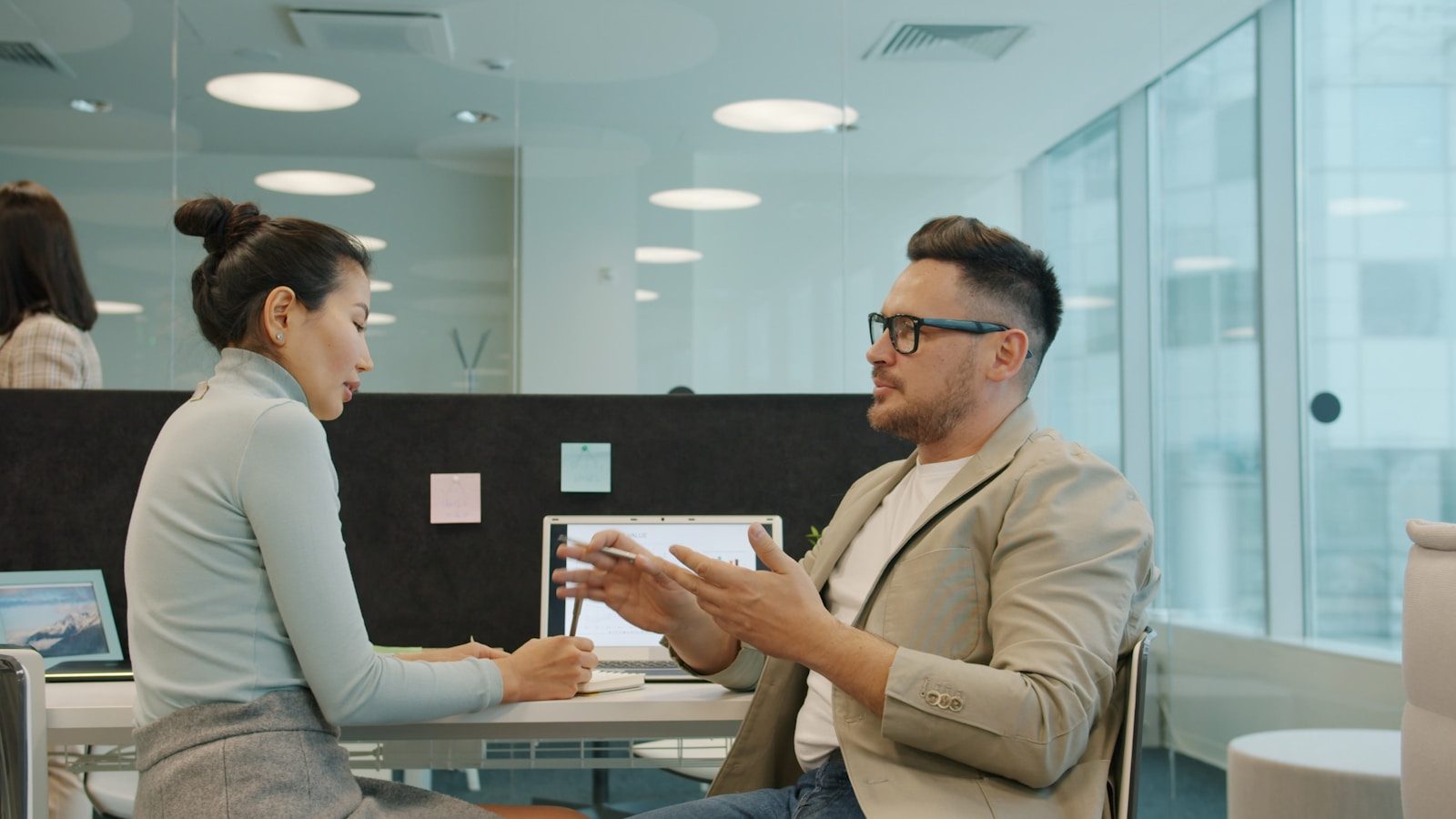 Two colleagues discussing work in a modern office.