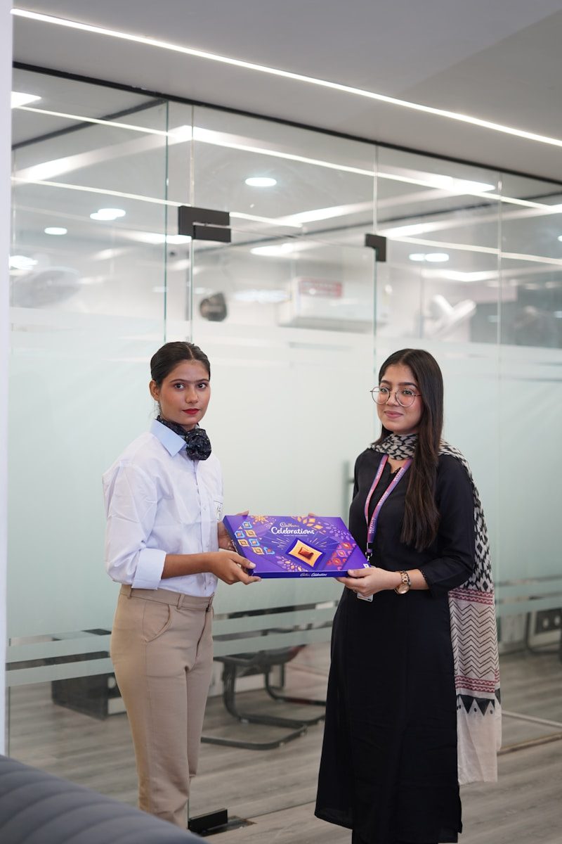 Two women holding a gift box in an office.